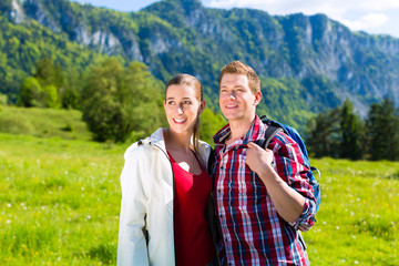 Paar läuft auf Wiese vor Bergpanorama