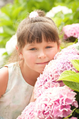 Fototapeta premium little happy girl in garden with flowers
