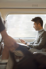 Young man sitting on a train using his phone