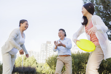 Granddaughter with grandparents playing Frisbee in the park 