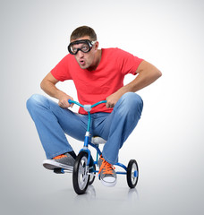 The curious man on a children's bicycle - obrazy, fototapety, plakaty