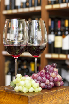 Copas de vino tinto, botella y uvas en vineria