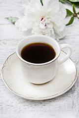 Cup of coffee and white peony on wooden rustic table