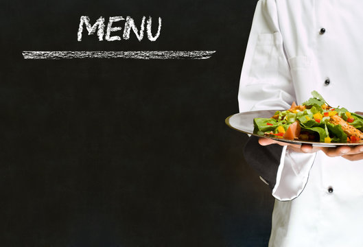 Chef with healthy salad food on chalk blackboard menu background