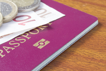 British passport with  Euro coins and notes on wood table