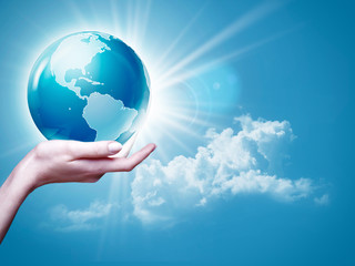 Female arm holding Earth  globe against blue skies, environmenta