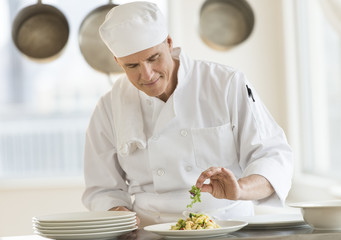 Chef Garnishing Dish In Commercial Kitchen