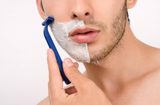 Young man shaving his beard in the morning with a razor