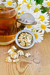 Fototapeta na wymiar Herbal tea from chamomile dry in a strainer with mug