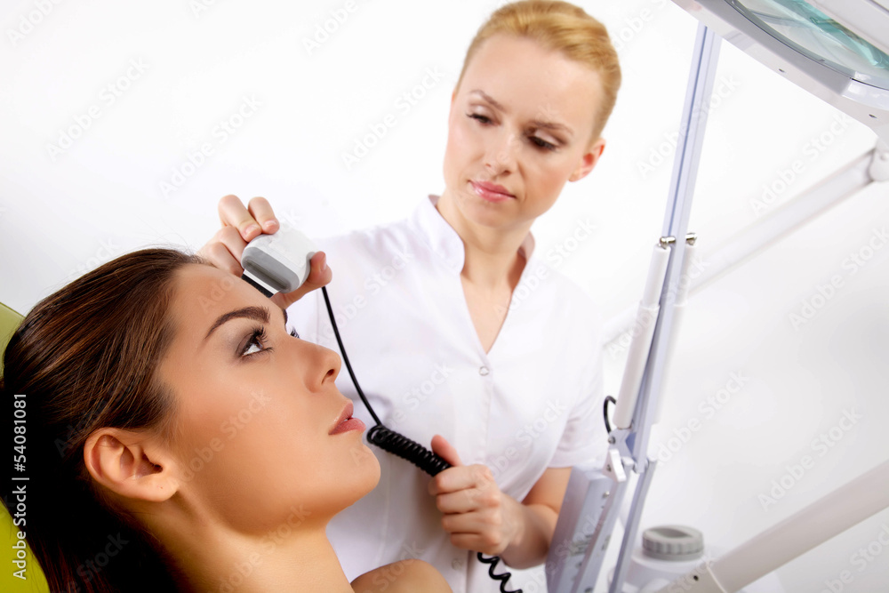 Wall mural woman having a stimulating facial treatment from a therapist