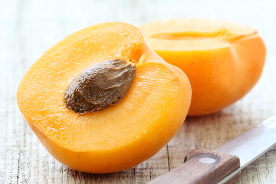 Fresh juicy apricot cut in half on a rustic wooden table