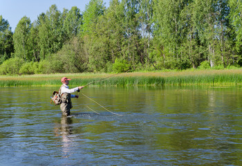 Obraz na płótnie Canvas Fisherman catches of chub fly fishing in the Chusovaya river