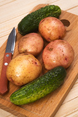 Fresh potatoes and cucumbers on a wooden stand