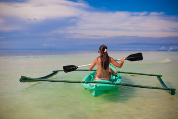 Rear view of a young woman kayaking in the clear sea