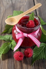 Raspberry jam with fresh raspberries and green leaves 