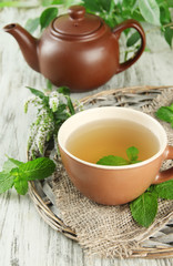 Teapot and cup of herbal tea with fresh mint flowers