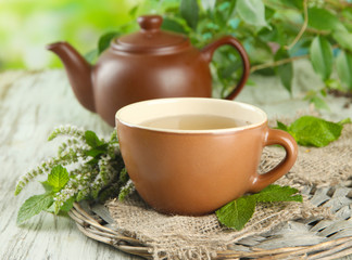 Teapot and cup of herbal tea with fresh mint flowers