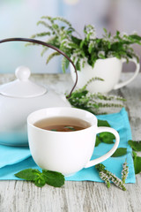 Teapot and cup of herbal tea with fresh mint flowers