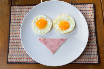 breakfast smiley face with bacon and fried eggs on white plate
