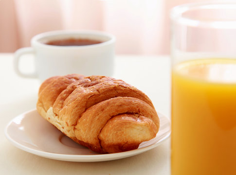 Glass of refreshing orange fruit juice and croissant
