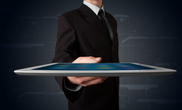 Businessman holding a white modern tablet with blurry apps