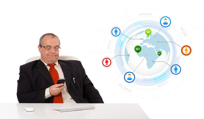 businessman sitting at desk and holding a mobilephone with globe