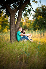 Young loving couple sitting under a tree