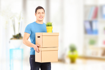 Smiling guy carrying removal boxes during moving