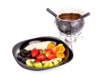 Chocolate fondue with fruits isolated on white