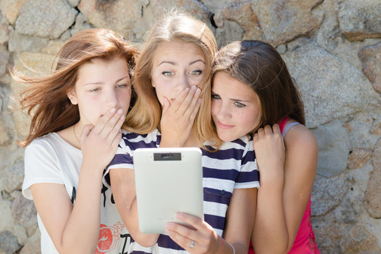 Three scared teen girl friends and tablet computer