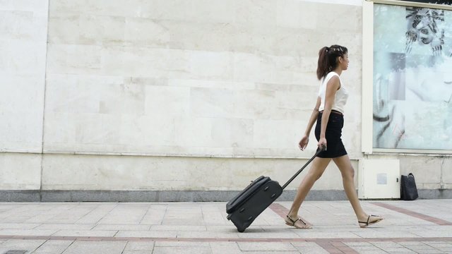 Young woman with luggage walking.