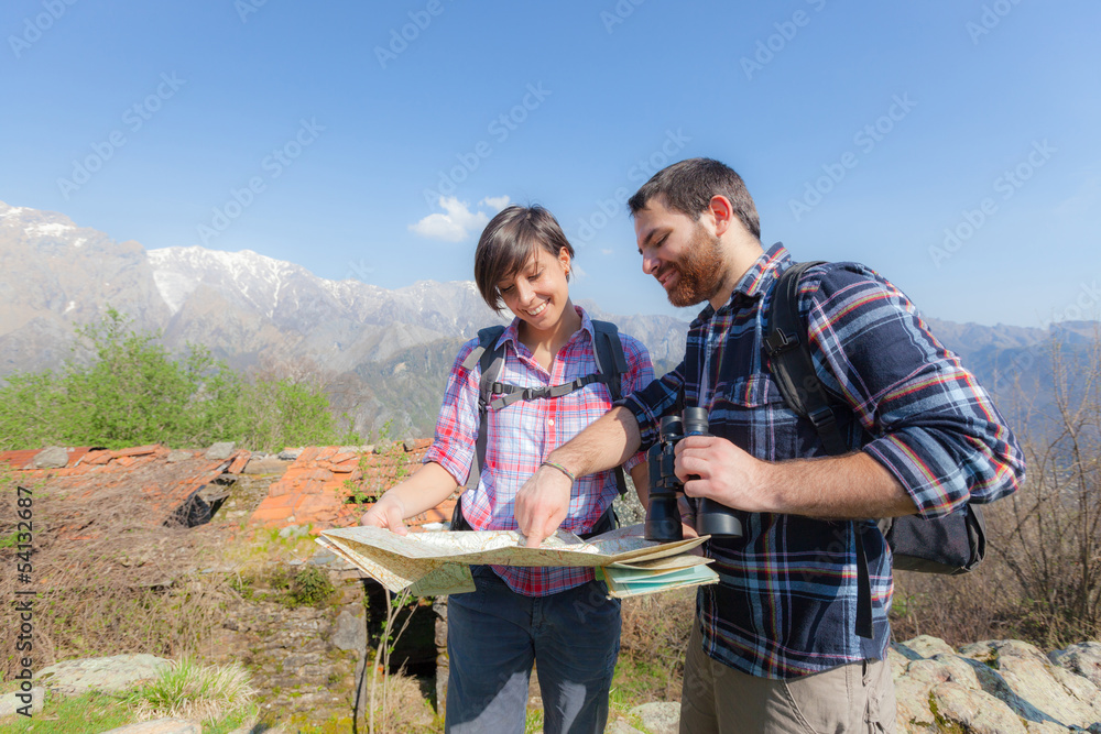 Wall mural young couple hiking looking at map