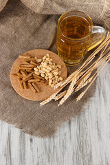 Beer in glass, crackers and nuts on bagging on wooden table