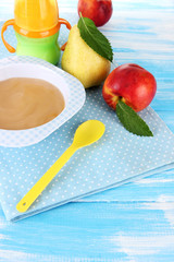 Tasty baby fruit puree and baby bottle on wooden table