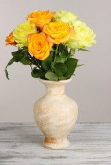 Beautiful bouquet of roses in vase on table on gray background