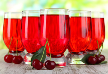 Glasses compote on wooden table on nature background