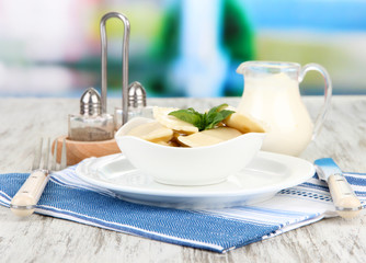 Tasty dumplings on white plate, on bright background
