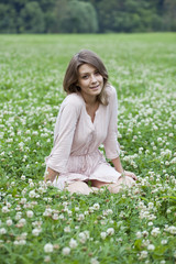 Portrait of young woman sitting on a green lawn