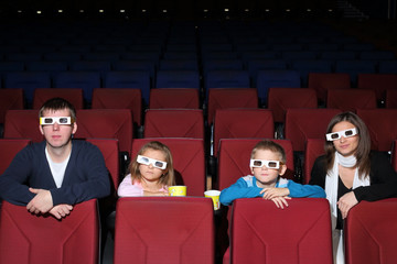 Family watching a movie in 3D cinema with popcorn