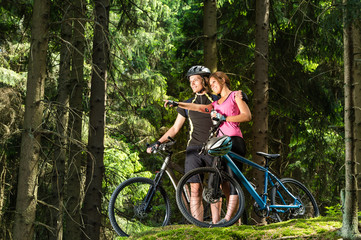 Smiling teen cyclists standing and pointing