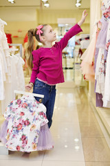Little girl, holding hangers with light-violet skirt