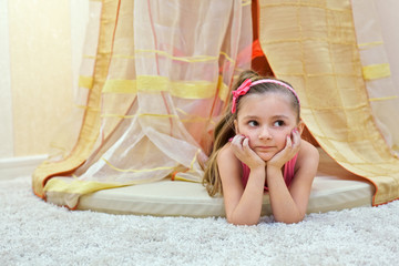 Little girl lies on her stomach, propping face with her hands © Pavel Losevsky