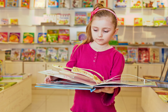 Little girl views fold-out book on anatomy in book department