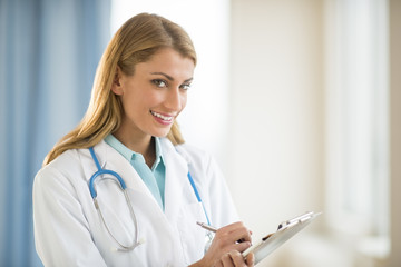 Confident Doctor Holding Clipboard In Clinic