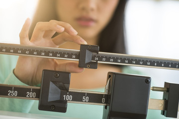 Midsection Of Woman Adjusting Weight Scale