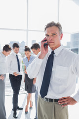 Serious boss on the phone standing in a modern office