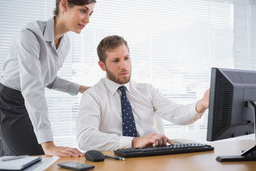 Businessman showing his colleague something on computer