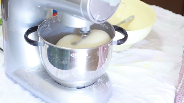 Old woman using machine to kneading dough for bread and pizza