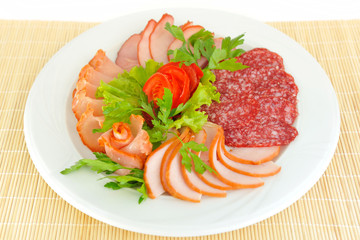 Dish with pastrami and salami slices decorated with greens.
