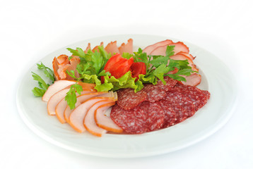 Pastrami and salami slices decorated with greens and tomato.